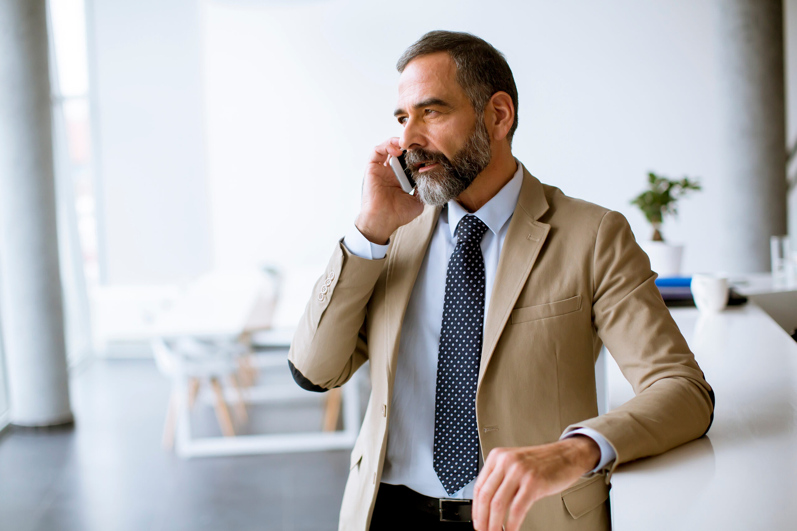 Senior Businessman Using Mobile Phone In Modern Office